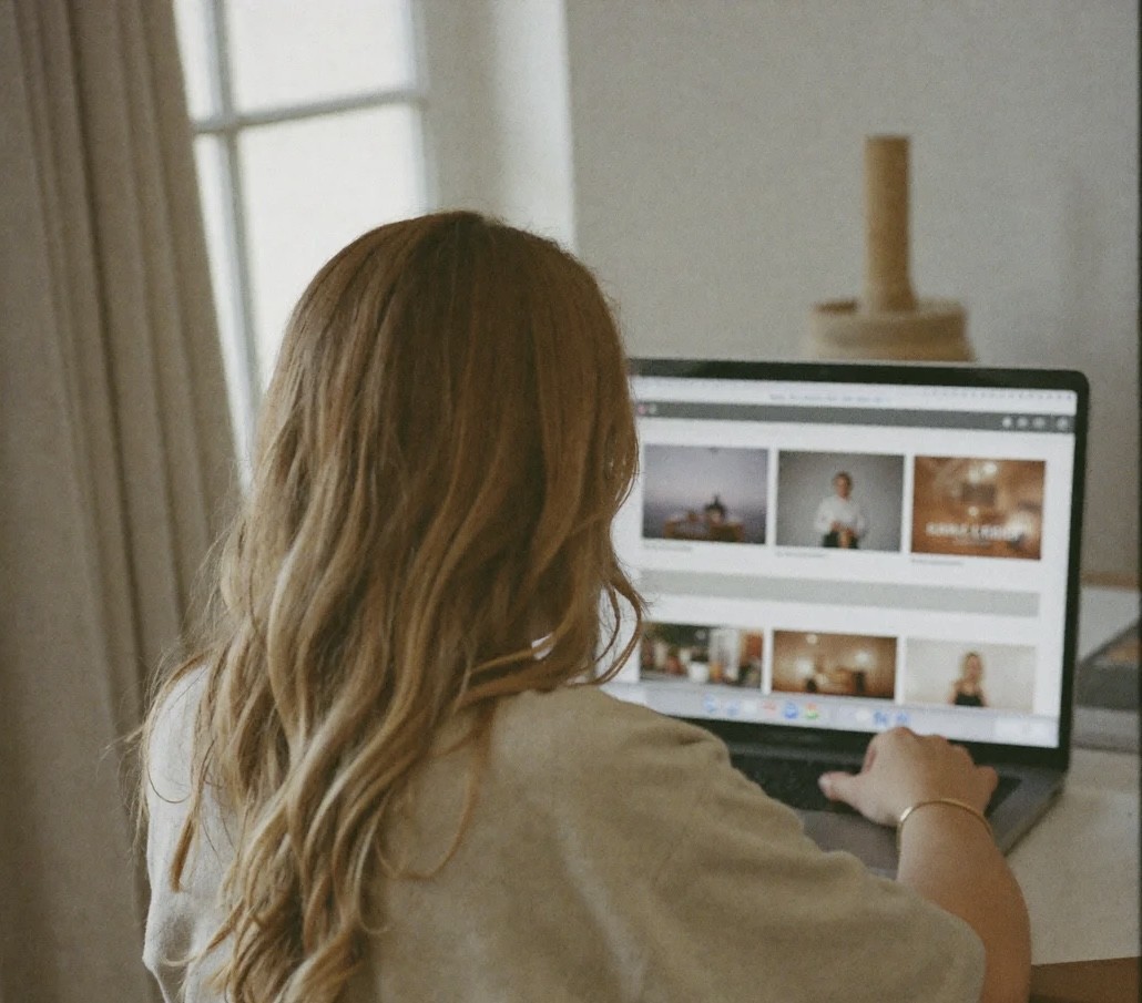Deb working at her laptop by the window, seen from behind